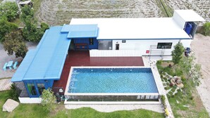 A modern house with a swimming pool, a blue roof, and a garden. - The White House P&N Hotel Chiang Rai (Wiang Chai)