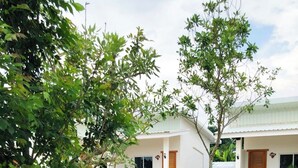 A garden with a wooden swing set, rocks, and a pathway leading to a building with a white exterior and wooden doors. - The White House P&N Hotel Chiang Rai (Wiang Chai)