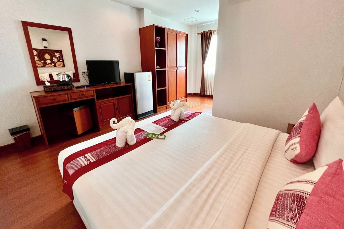 A hotel room with a bed, a desk with a computer, a television, and a wardrobe.