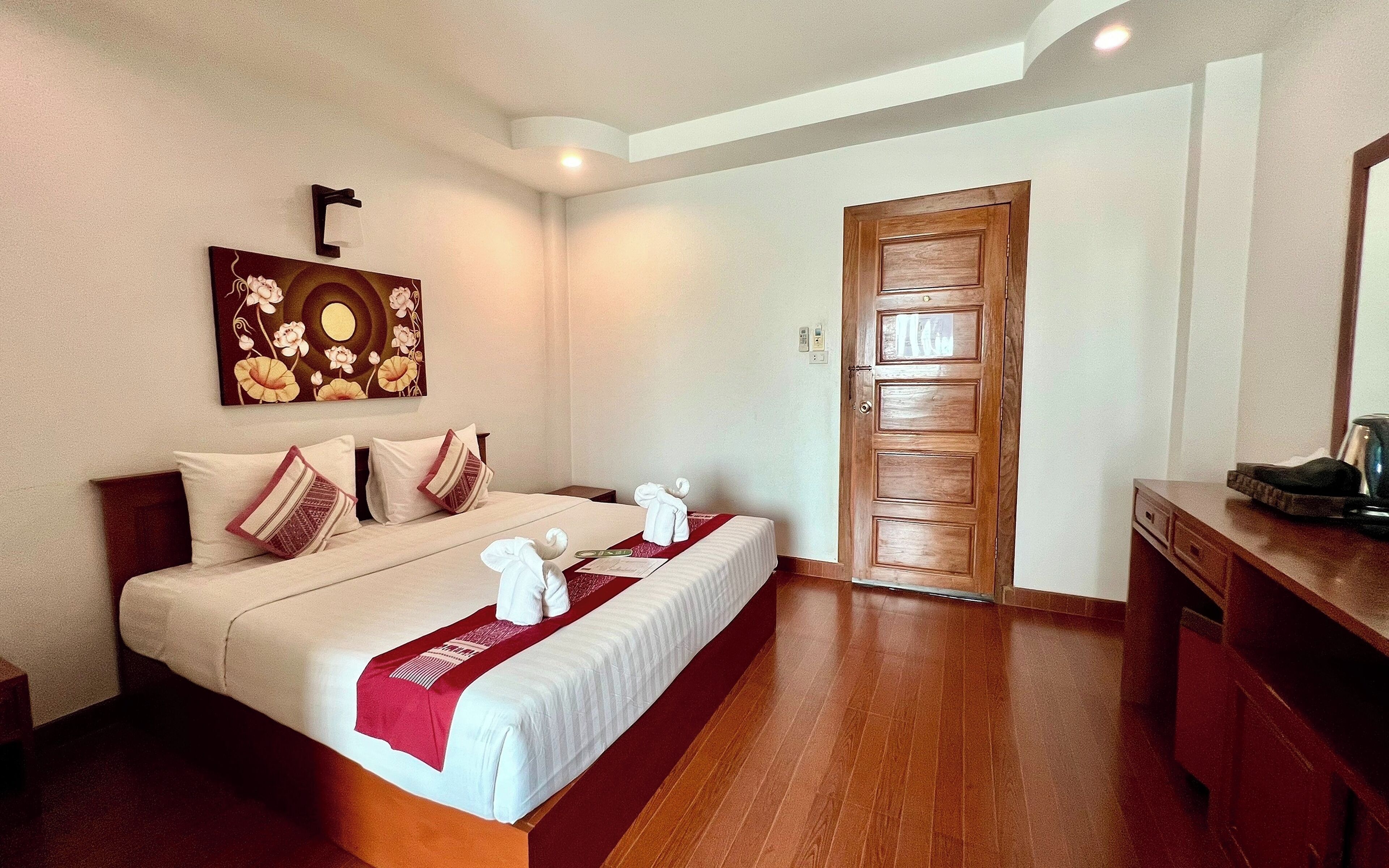 Una habitación de hotel con una cama de madera, un plaid rojo y un cuadro en la pared.