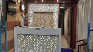 Uma área de recepção com parede estampada, balcão e uma cadeira.