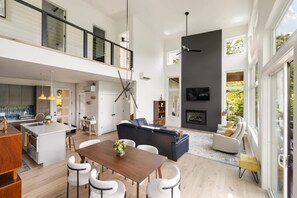 Uma sala de estar ampla com uma mesa de jantar, sofás e lareira.