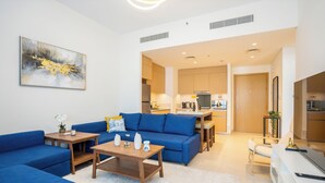 A modern living room with a blue sofa, wooden coffee table, and a painting on the wall.