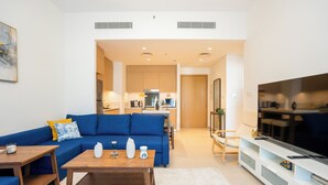 A modern living room with a blue sofa, wooden coffee table, and a flat-screen TV.