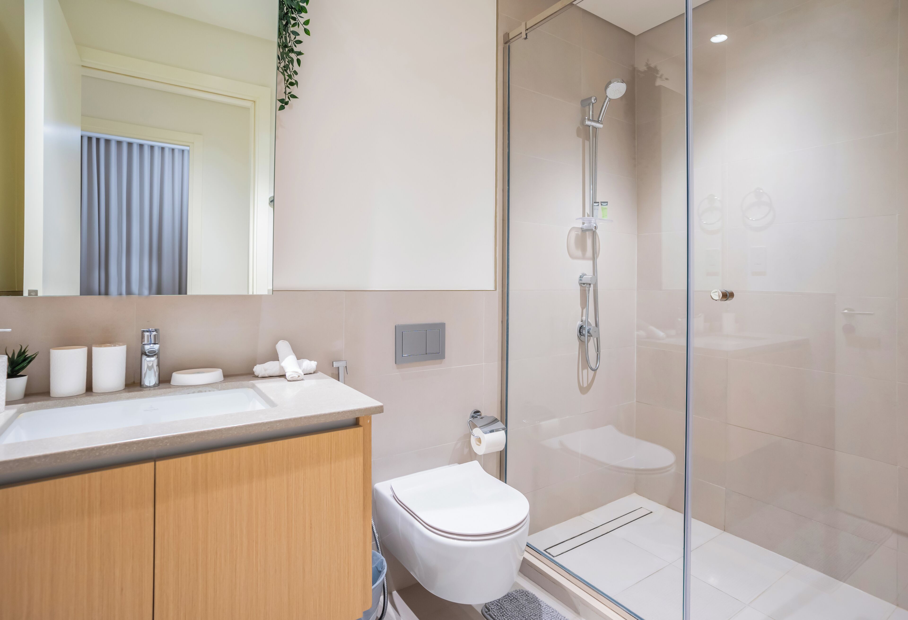 A modern bathroom with a glass shower enclosure, a white sink, and a toilet.