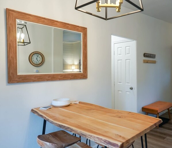 A wooden table with a bowl and a clock on the wall above it.