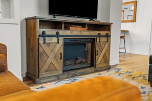 A living room with a fireplace, a mounted television, and a patterned rug.