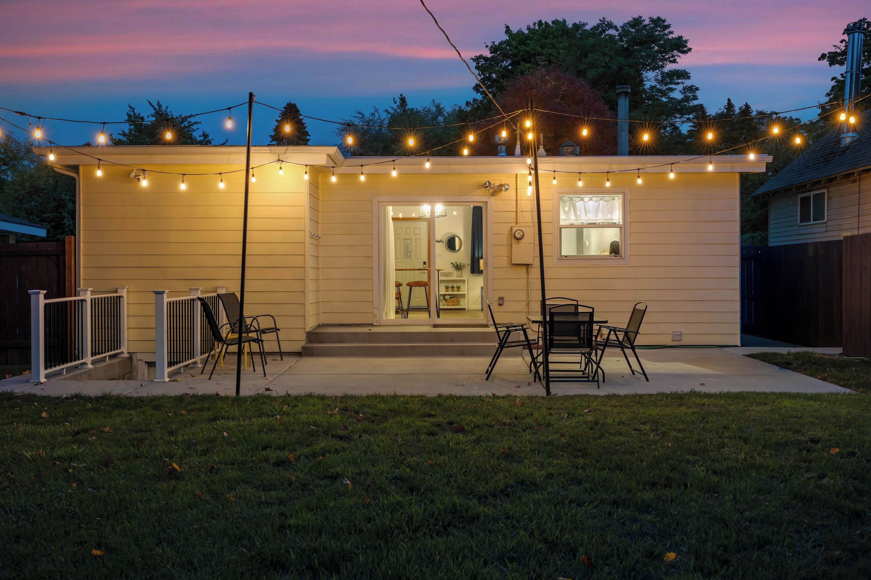 Une maison dotée d’un patio couvert, d’un espace salon extérieur et de guirlandes lumineuses.
