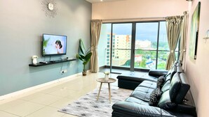 Un salon moderne avec un téléviseur, un canapé et une vue sur la ville.