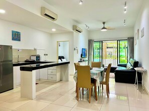 A modern kitchen with a dining area, a sofa, and a ceiling fan. - Capital O 90987 The Loft Residences Homestay @ Imago Shopping Mall 2 (Kota Kinabalu)