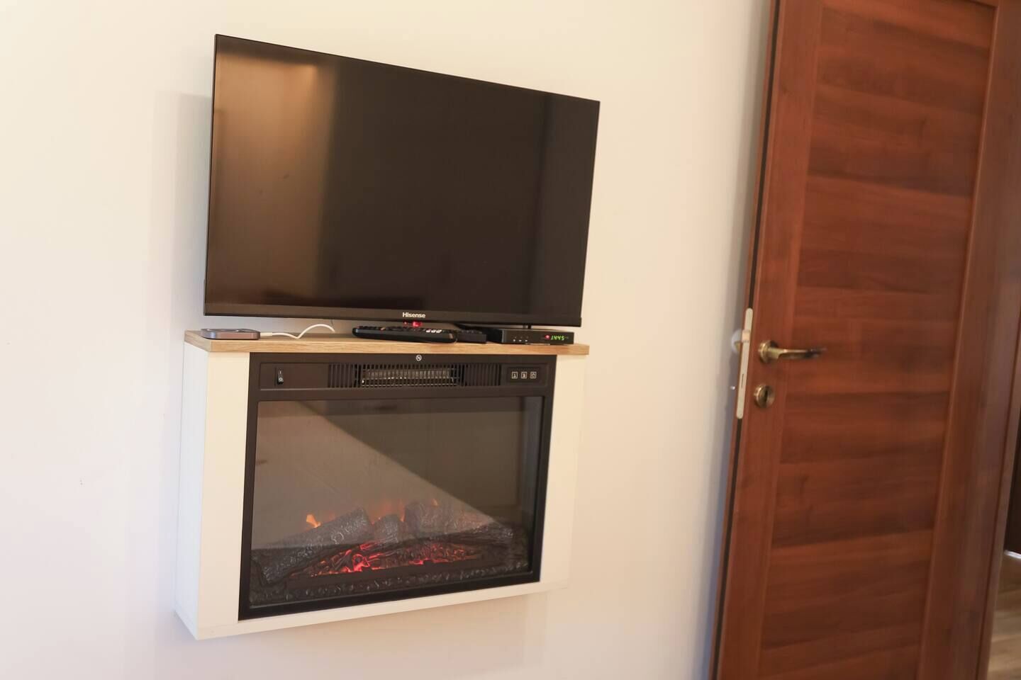 Un téléviseur à écran plat fixé au-dessus d’une cheminée, avec une télécommande et un lecteur DVD placés en dessous.
