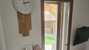 Olohuone, jossa on takka, kello ja lasiliukuovi, joka johtaa terassille.