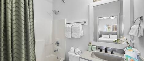 A modern bathroom with a bathtub, toilet, sink, and a large mirror with lights.