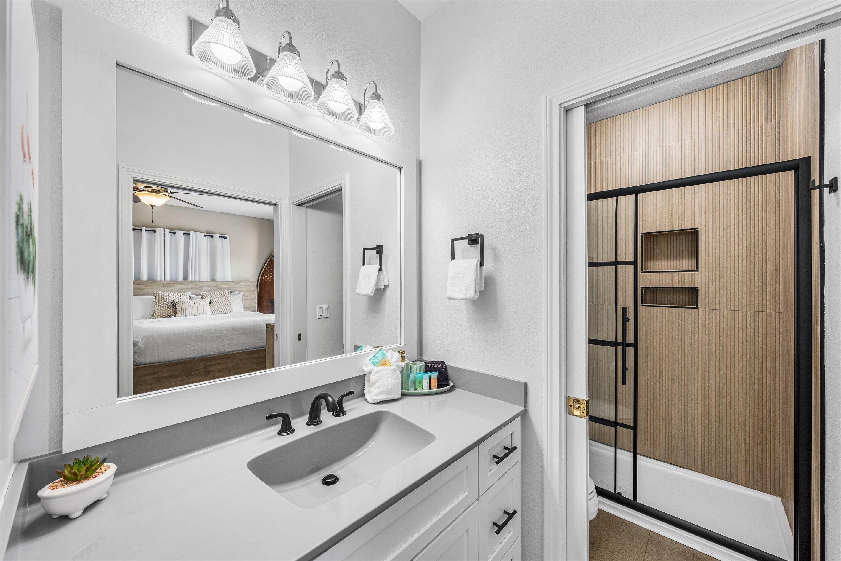 A modern bathroom with a large mirror, a sink, and a shower area.