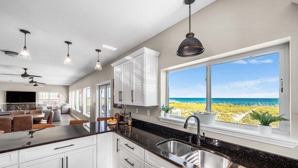 A modern kitchen with a large island, white cabinetry, and a view of the beach. - Lowe Tide, Fantastic Private Beach Front Home. 5 Stars! (Navarre)