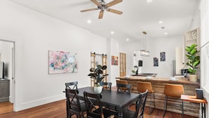 A modern kitchen with a central island, wooden flooring, and a ceiling fan. - Marigny Retreat | Steps to Trolley, French Quarter (New Orleans)