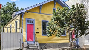 A yellow house with a red door, blue trim, and a small front porch. - Marigny Retreat | Steps to Trolley, French Quarter (New Orleans)