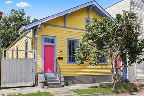 A yellow house with a red door, blue trim, and a small front porch. - Marigny Retreat | Steps to Trolley, French Quarter (New Orleans)