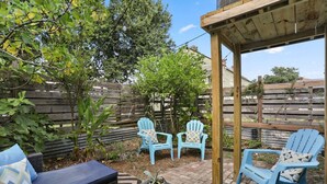 A patio area with blue Adirondack chairs, a wicker sofa, and a small table with a potted plant. - Marigny Retreat | Steps to Trolley, French Quarter (New Orleans)