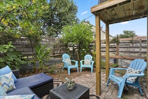 A patio area with blue Adirondack chairs, a wicker sofa, and a small table with a potted plant. - Marigny Retreat | Steps to Trolley, French Quarter (New Orleans)