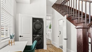 Une cuisine moderne avec un coin repas, un lave-linge et un escalier.