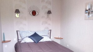 A bedroom with a bed, two bedside lamps, a wall-mounted eye decoration, and a hanging lamp. - Maison en Bordure de mer (Sotteville-sur-Mer)