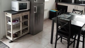 A compact kitchen with a refrigerator, microwave, and a small dining table with chairs. - Maison en Bordure de mer (Sotteville-sur-Mer)