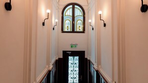 A grand staircase with a balustrade, a decorative ceiling, and wall-mounted lighting fixtures. - Ecletico Villa (Bucharest)