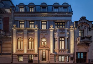 Ein historisches Gebäude mit aufwendigen architektonischen Details, darunter gewölbte Fenster und dekorative Stuckarbeiten.