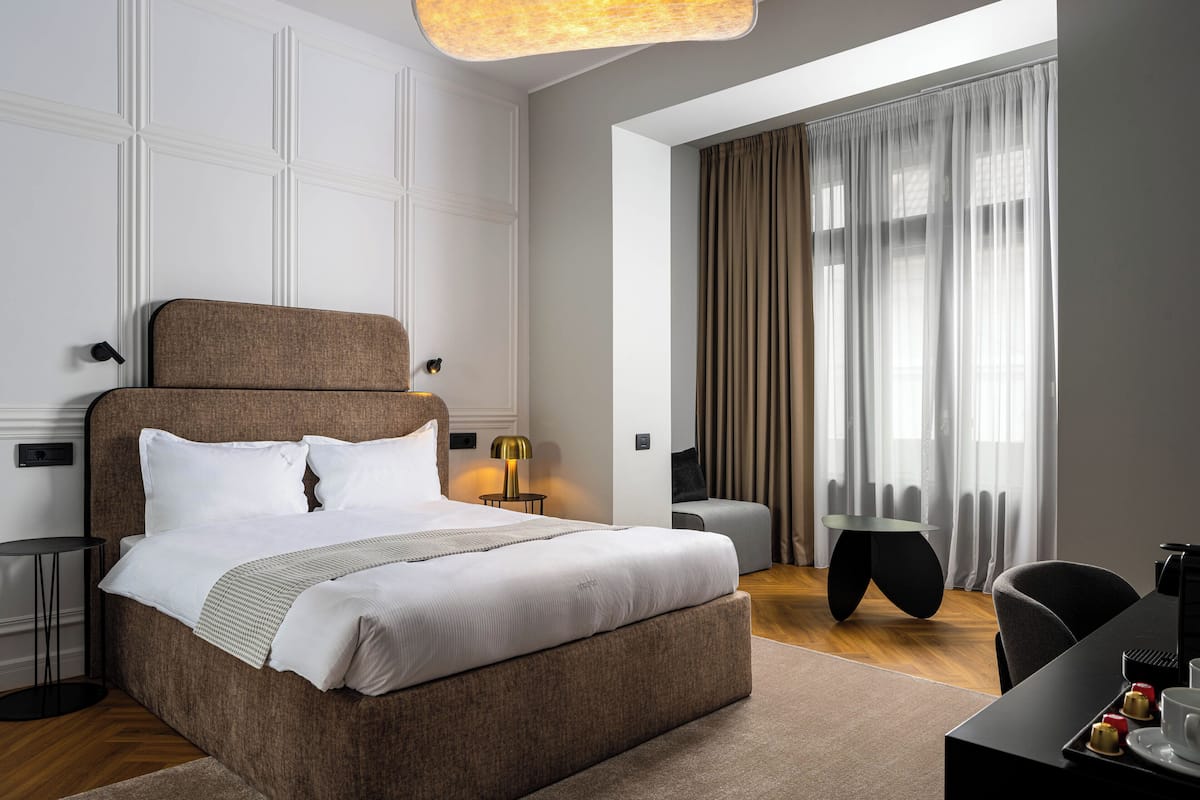 A modern hotel room with a large bed, a desk, and a chair.