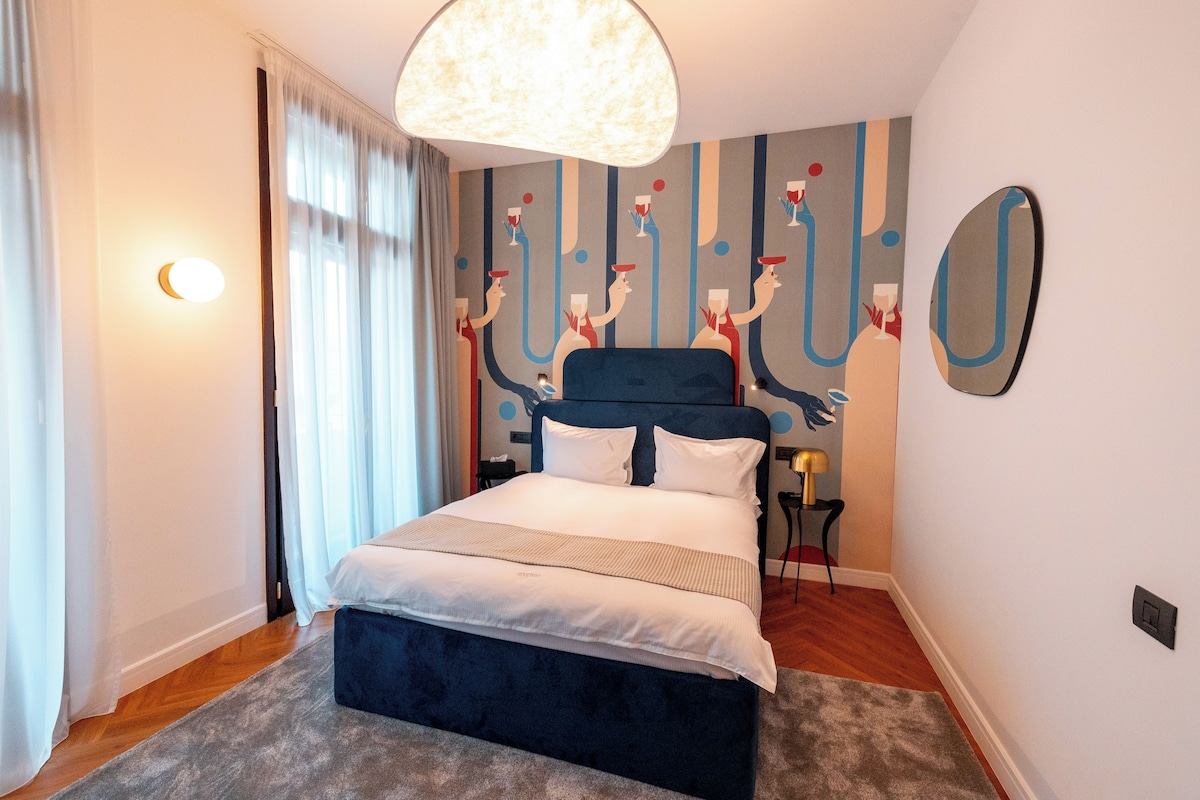 A modern bedroom with a large bed, a unique wall mural, and a chandelier.