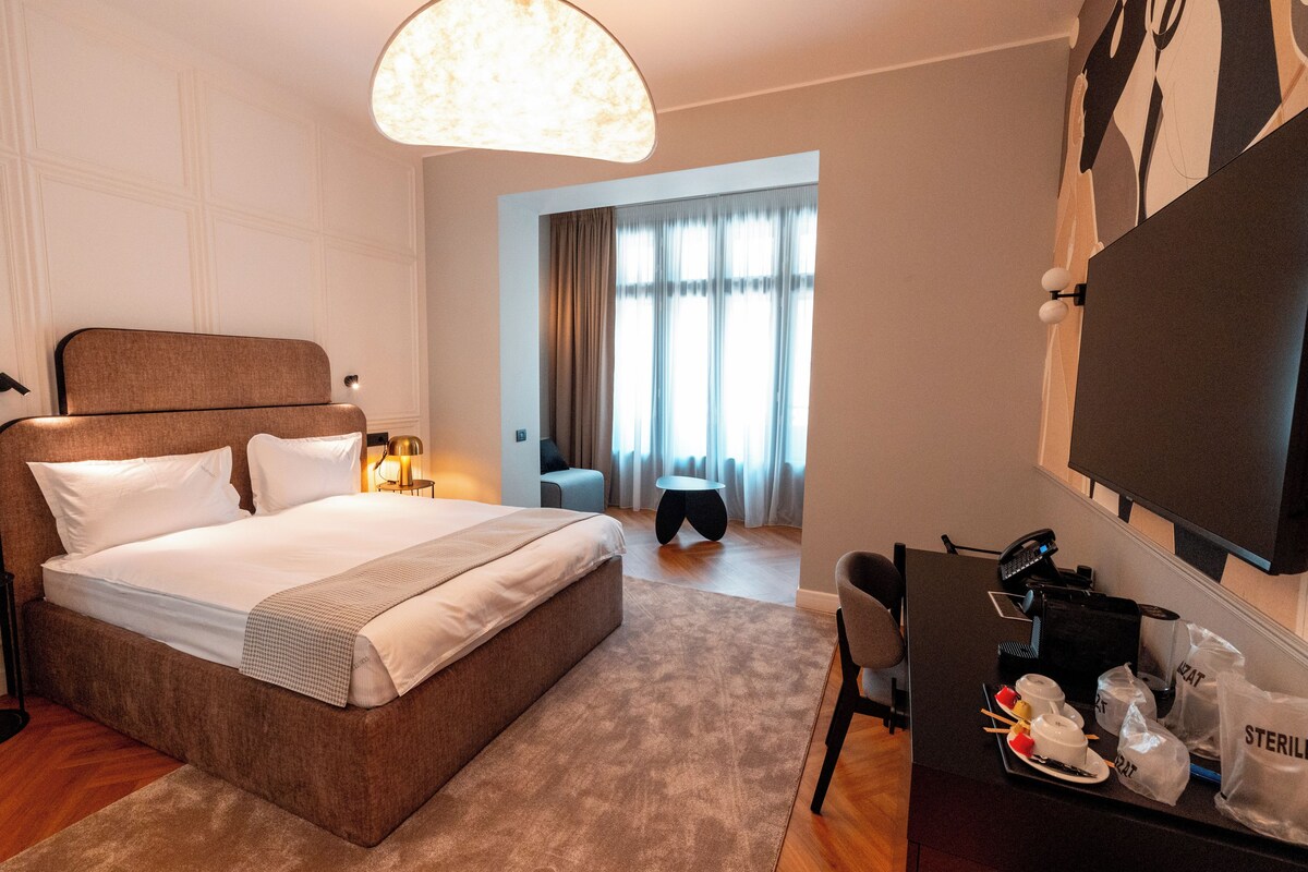 Une chambre d’hôtel avec un grand lit, un bureau avec des articles de toilette, une chaise et un téléviseur fixé au mur.
