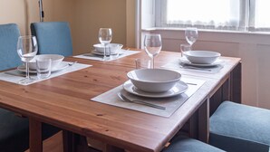 A dining table set with plates, bowls, and wine glasses, flanked by chairs and a bookshelf. - Italianway Easy - Cipro 5 (Milan)