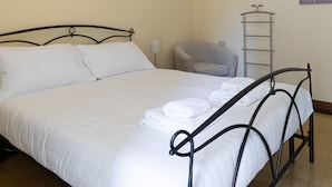 A neatly made bed with white linens, a metal frame, and a small bedside table with a lamp. - Italianway Easy - Cipro 5 (Milan)