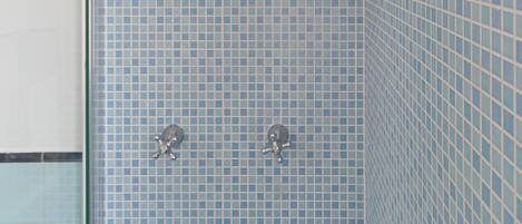 Un bagno con pareti piastrellate di blu, una doccia e una porta in vetro.