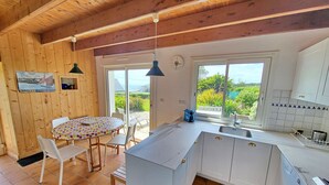 A kitchen with a large island, white cabinets, and a dining area with a table and chairs. - 391-Beautiful fisherman's house, closer to the beach with sea view (Primelin)