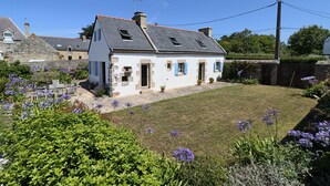 A two-story house with a sloped roof, a small front yard, and a garden with purple flowers. - 391-Beautiful fisherman's house, closer to the beach with sea view (Primelin)