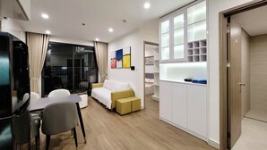 Un salon moderne comprenant un canapé, une table à manger et un téléviseur. Une porte coulissante donne accès à une chambre à coucher équipée d’un lit et d’une armoire.