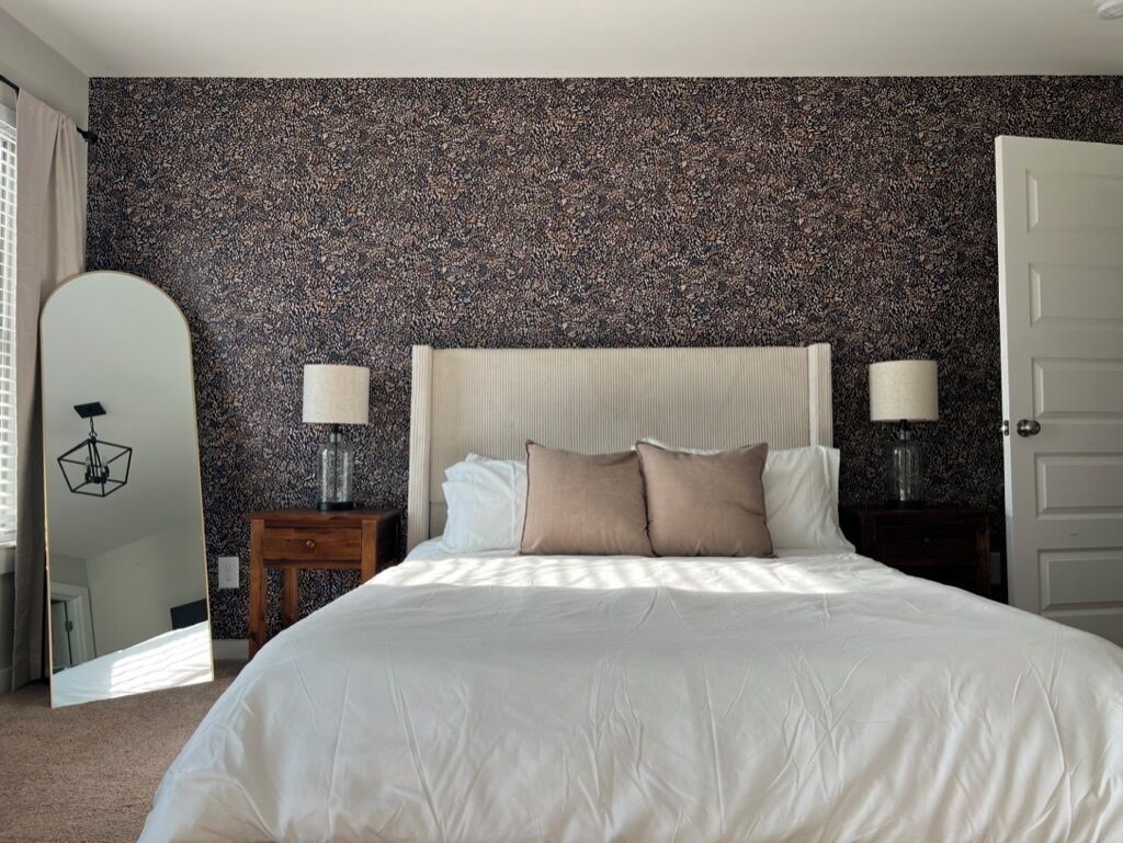 A bedroom with a large bed, two bedside tables with lamps, a mirror, and a door.