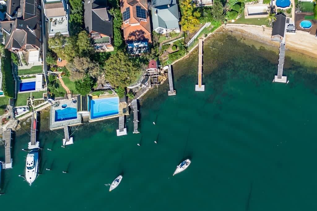 An aerial view of a marina with boats docked, surrounded by residential houses and a clear view of the water.