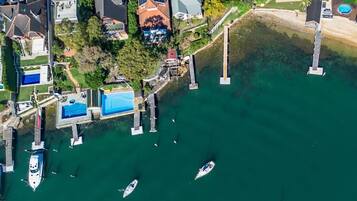 An aerial view of a marina with boats docked, surrounded by residential houses and a clear view of the water.