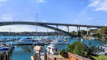 A marina with boats docked, a bridge in the background, and a pool area with a fence.