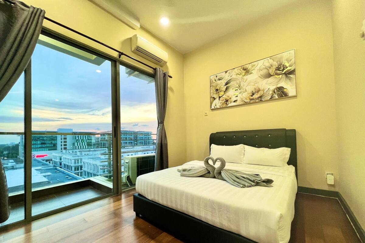 Una habitación de hotel con una cama grande, vistas de la ciudad a través de una puerta corredera y una obra de arte floral en la pared.