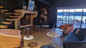 A modern interior with a fireplace, seating area, and a view of the water. - La Villa Mandragore (Hyères)