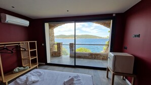 A hotel room with a bed, a wardrobe, a seating area, and a balcony with a view of the sea. - La Villa Mandragore (Hyères)