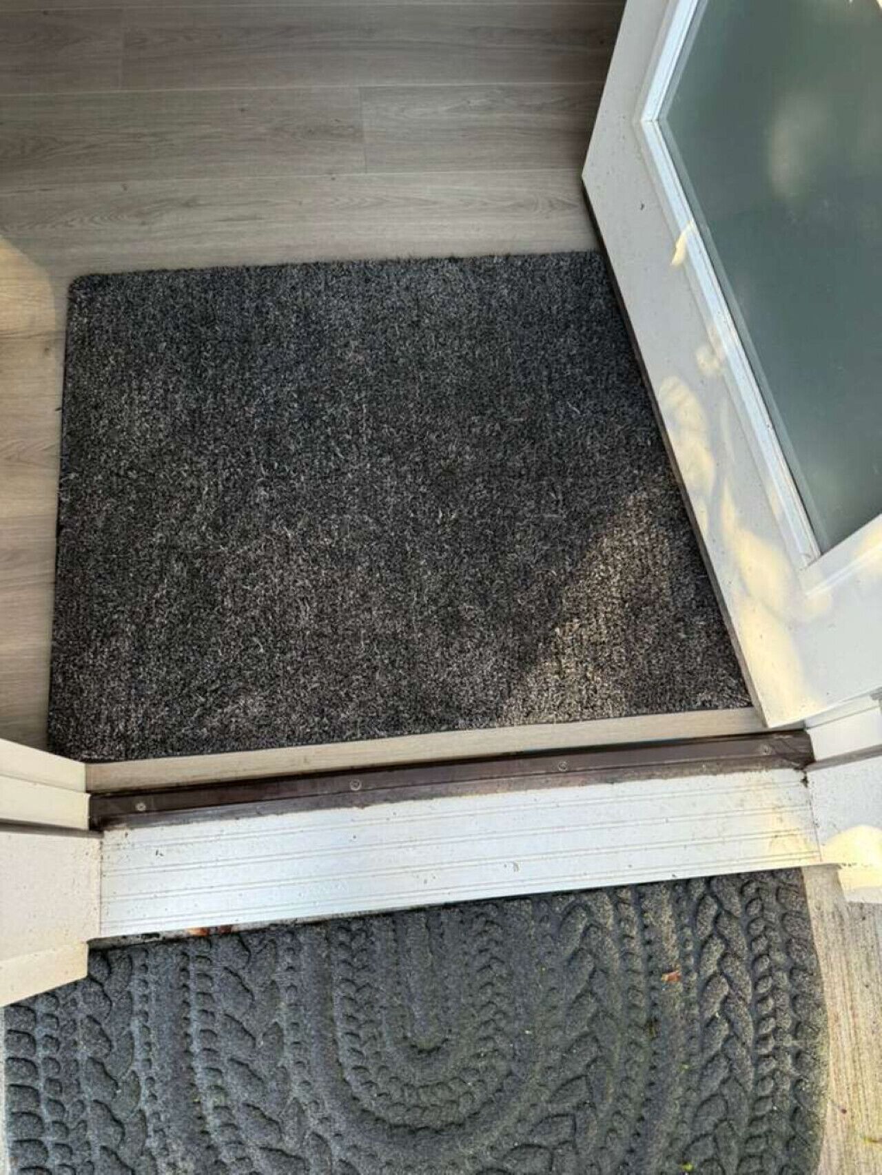 Un plancher en bois, avec un paillasson et un tapis à motifs.