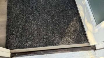 Un plancher en bois, avec un paillasson et un tapis à motifs.