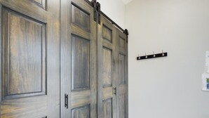A room with a large wooden wardrobe, a coat rack, and a white wall.