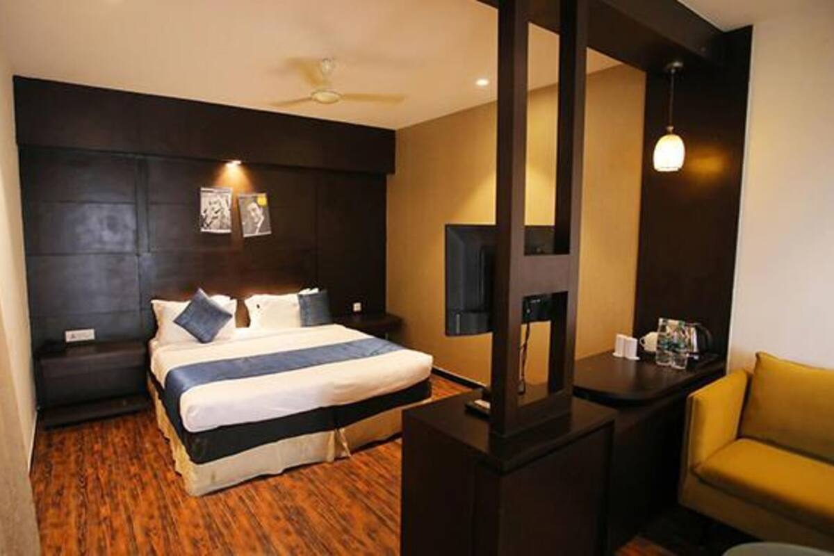 A hotel room with a bed, a desk, a chair, and a ceiling fan.