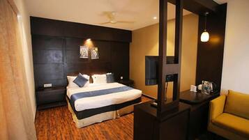 A hotel room with a bed, a desk, a chair, and a ceiling fan.